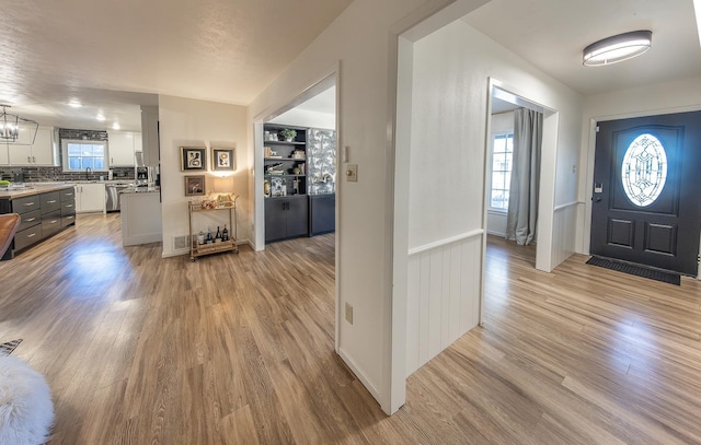 entryway with plenty of natural light, sink, and light hardwood / wood-style flooring