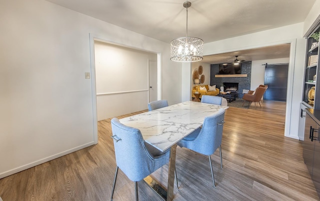 dining area featuring ceiling fan with notable chandelier, a fireplace, and hardwood / wood-style floors