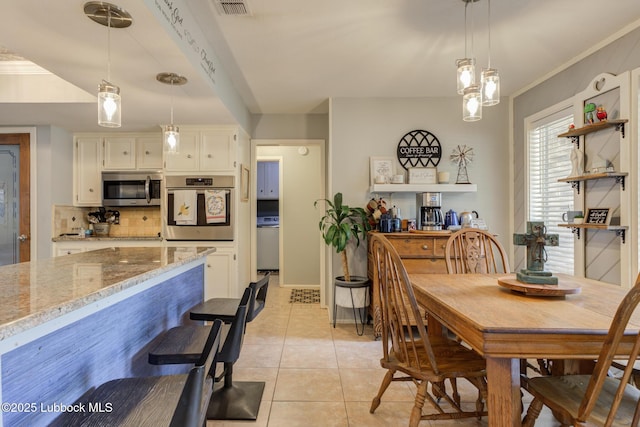 5417 89th St, Lubbock, TX 79424 - dining room featuring washer / clothes dryer, visible vents, light tile patterned floors, baseboards, and ornamental molding