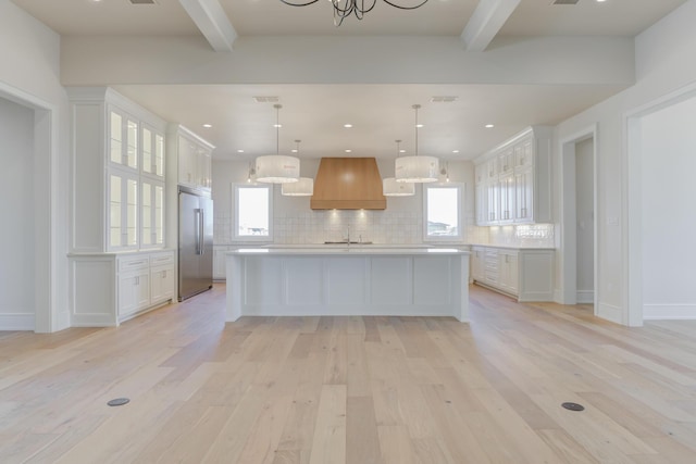 kitchen with custom exhaust hood, high end fridge, light countertops, and beam ceiling