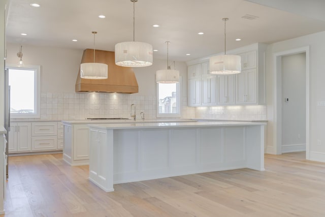 kitchen with light wood-style flooring, light countertops, backsplash, and a kitchen island