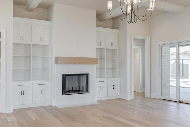 unfurnished living room featuring a fireplace with flush hearth, light wood-type flooring, an inviting chandelier, and beam ceiling