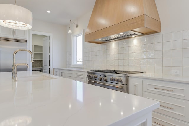 kitchen with custom range hood, premium appliances, a sink, and decorative backsplash