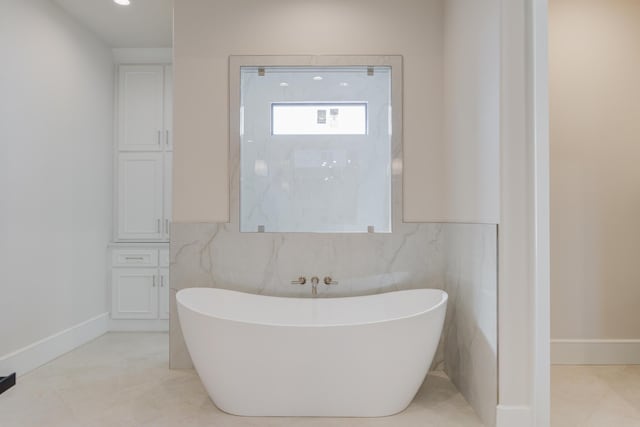 full bathroom featuring a soaking tub, baseboards, and tile patterned flooring