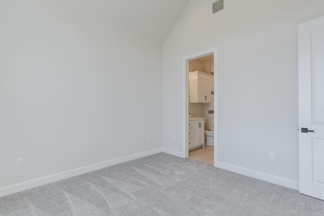unfurnished bedroom with baseboards, ensuite bath, visible vents, high vaulted ceiling, and light colored carpet