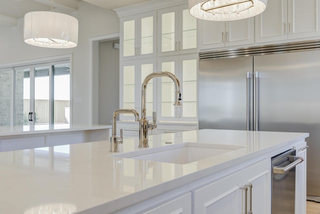 interior space with white cabinets, stainless steel built in fridge, pendant lighting, and a sink
