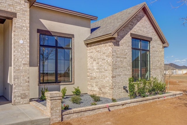 view of property exterior with stucco siding and brick siding