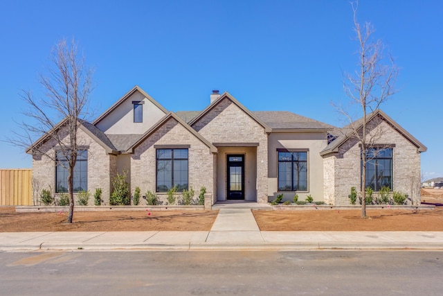 craftsman-style house with brick siding, roof with shingles, fence, and a chimney