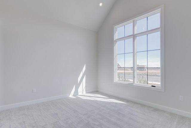 empty room with a healthy amount of sunlight, vaulted ceiling, and carpet