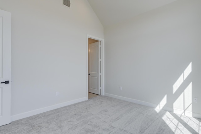 empty room featuring high vaulted ceiling, carpet flooring, baseboards, and visible vents