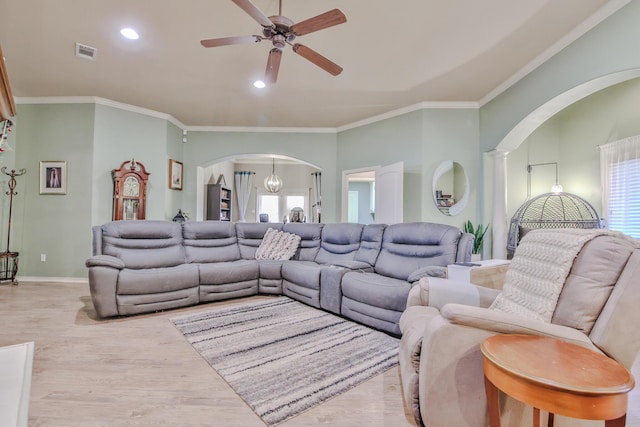 living area with visible vents, arched walkways, wood finished floors, and ornamental molding