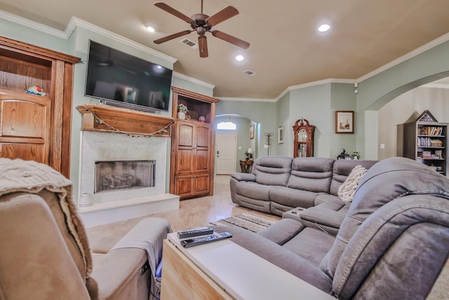 living room featuring visible vents, arched walkways, crown molding, light wood-style floors, and a high end fireplace