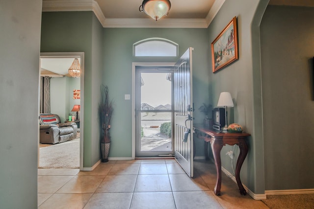 tiled foyer with baseboards, ornamental molding, and arched walkways