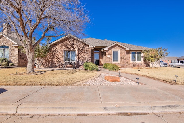 ranch-style home with roof with shingles and brick siding