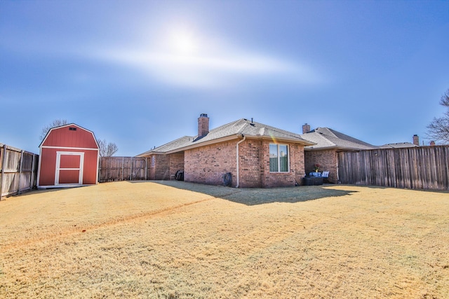 view of property exterior featuring an outbuilding, brick siding, a chimney, a storage unit, and a fenced backyard