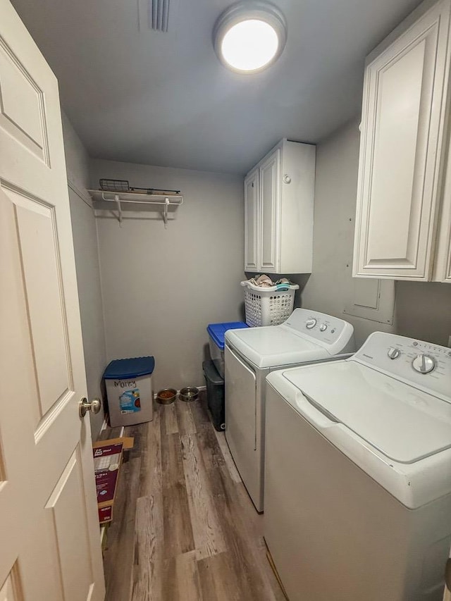 washroom with cabinets, washing machine and clothes dryer, and light wood-type flooring