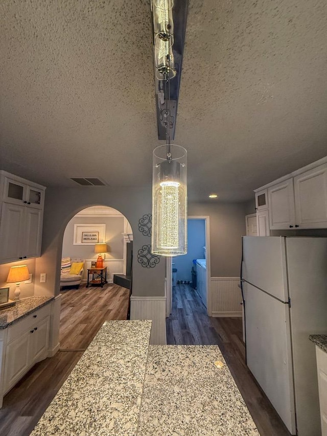 kitchen featuring white refrigerator, dark hardwood / wood-style floors, light stone counters, and white cabinets