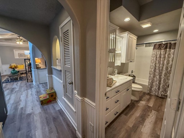full bathroom with toilet, wood-type flooring, shower / tub combo, vanity, and ceiling fan