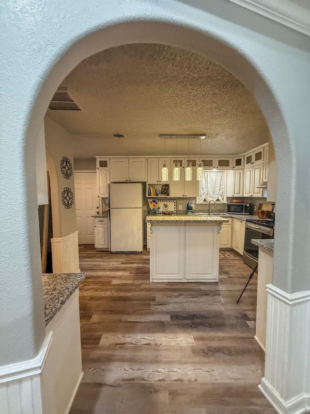 kitchen featuring stainless steel appliances, dark hardwood / wood-style flooring, stone countertops, and a textured ceiling