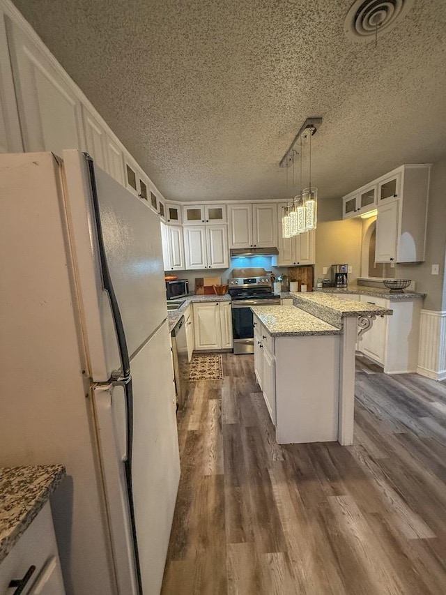 kitchen featuring hanging light fixtures, a kitchen island, stainless steel appliances, light stone counters, and a kitchen bar