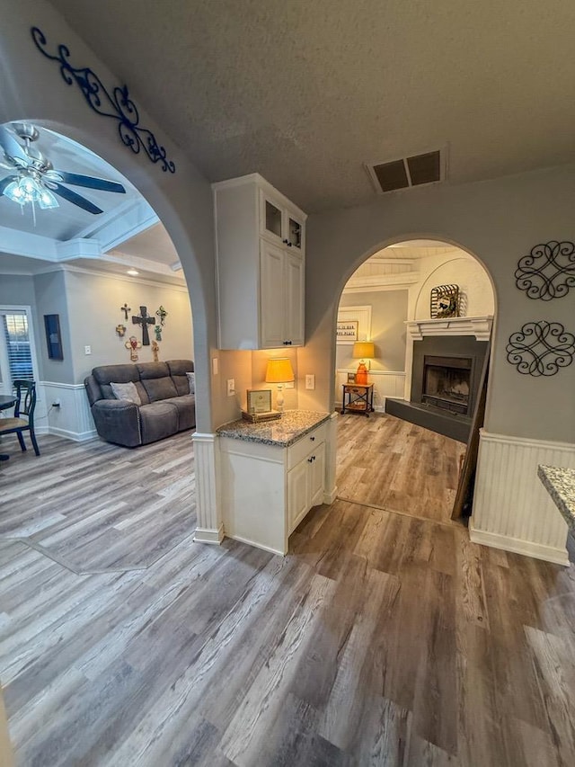 kitchen featuring white cabinetry, ceiling fan, light stone countertops, a textured ceiling, and light hardwood / wood-style flooring