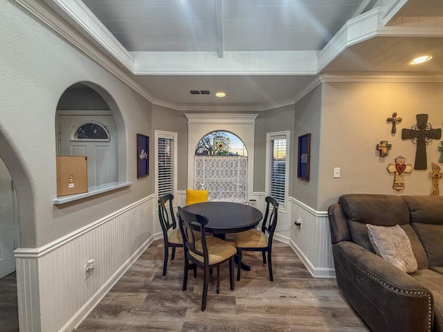dining room with hardwood / wood-style flooring, crown molding, and beam ceiling
