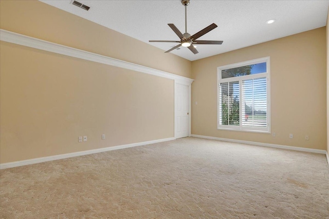 empty room with ceiling fan, light carpet, and a textured ceiling