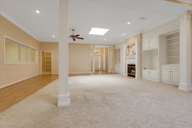 unfurnished living room featuring ceiling fan, ornamental molding, built in features, and ornate columns