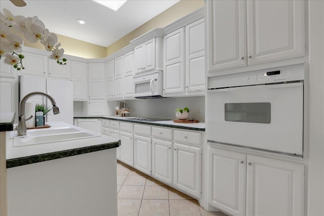 kitchen with light tile patterned flooring, sink, white cabinets, and white appliances