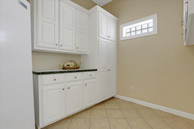 interior space with light tile patterned floors and white cabinets