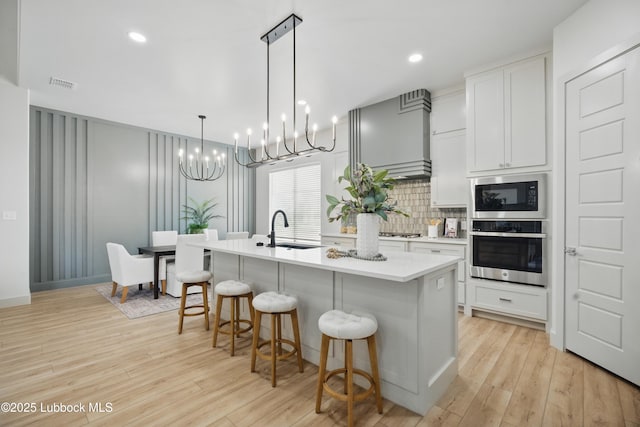 4614 138th Pl, Lubbock, TX 79424 - kitchen with appliances with stainless steel finishes, a chandelier, a kitchen breakfast bar, backsplash, and an island with sink