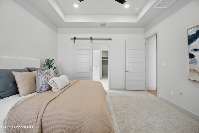 4614 138th Pl, Lubbock, TX 79424 - bedroom featuring a barn door, a tray ceiling, light colored carpet, and a walk in closet