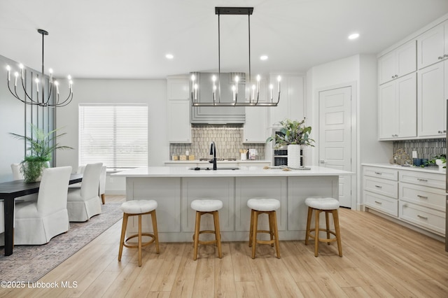 4614 138th Pl, Lubbock, TX 79424 - kitchen featuring a chandelier, light countertops, light wood-style floors, tasteful backsplash, and a breakfast bar