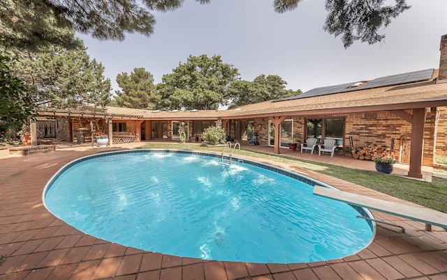 view of swimming pool featuring a patio and a diving board