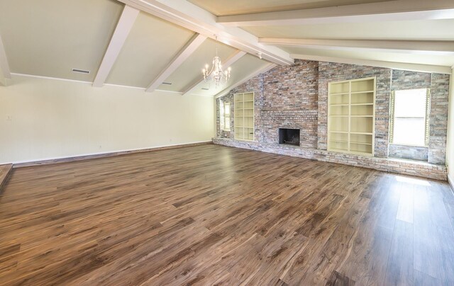 unfurnished living room featuring built in shelves, a chandelier, lofted ceiling with beams, a brick fireplace, and hardwood / wood-style flooring