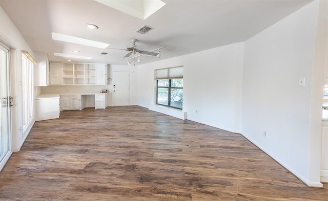 unfurnished living room with dark hardwood / wood-style flooring, built in desk, a skylight, and ceiling fan