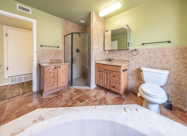 bathroom featuring vanity, toilet, a shower with shower door, and tile walls