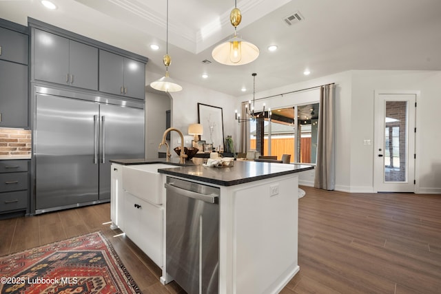 4606 138th Pl, Lubbock, TX 79424 - kitchen with appliances with stainless steel finishes, gray cabinetry, dark countertops, dark wood-type flooring, and a kitchen island with sink