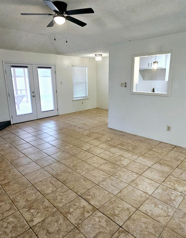 empty room featuring ceiling fan, a wealth of natural light, a textured ceiling, and french doors