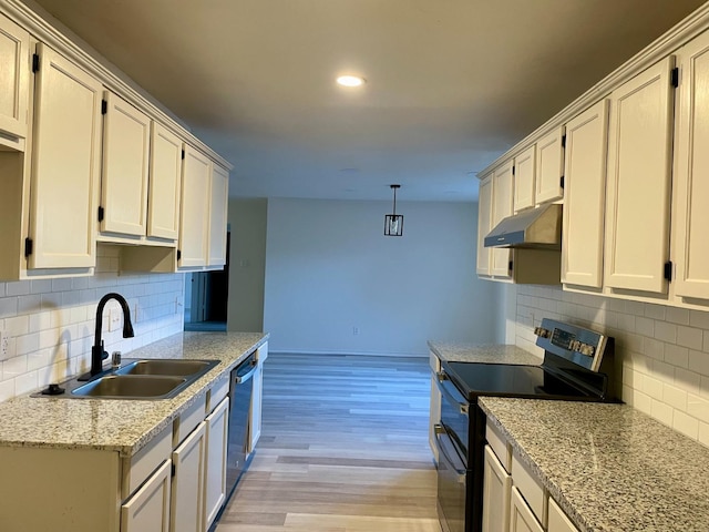 kitchen featuring under cabinet range hood, a sink, appliances with stainless steel finishes, light wood-type flooring, and decorative light fixtures