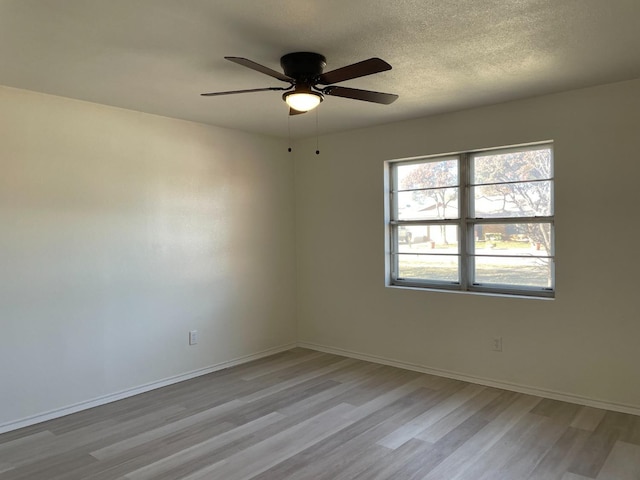 unfurnished room with light wood finished floors, ceiling fan, baseboards, and a textured ceiling