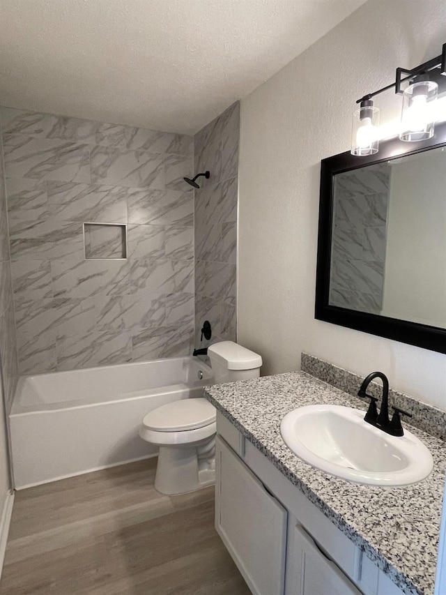 bathroom featuring bathing tub / shower combination, toilet, wood finished floors, a textured ceiling, and vanity