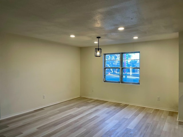 unfurnished room featuring light hardwood / wood-style floors and a textured ceiling