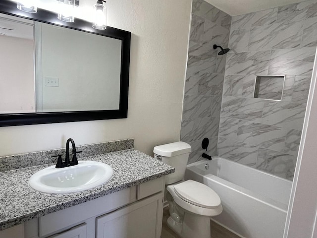 full bathroom featuring tiled shower / bath, vanity, and toilet