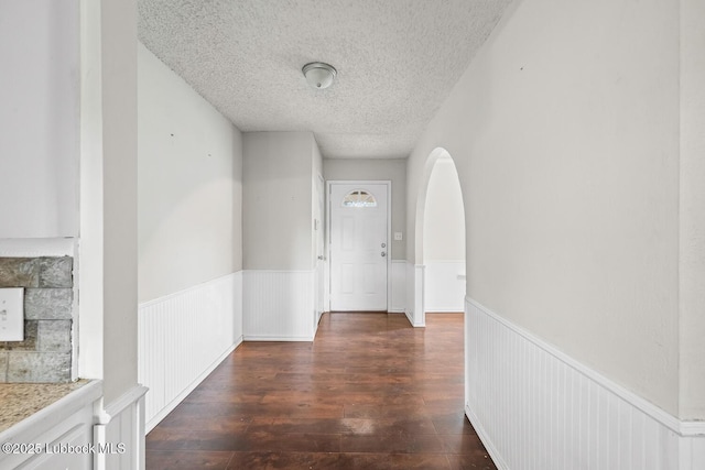 3415 39th St, Lubbock, TX 79413 - hall featuring a wainscoted wall, a textured ceiling, wood-type flooring, and arched walkways