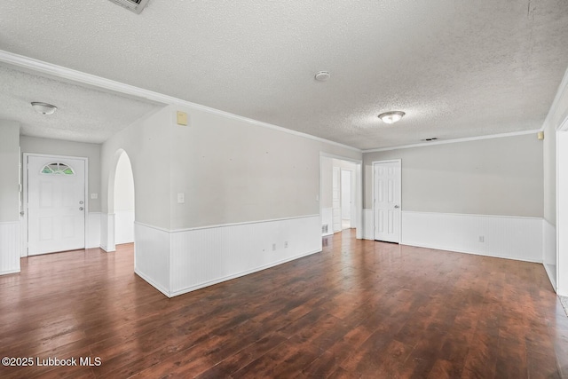3415 39th St, Lubbock, TX 79413 - unfurnished room with a textured ceiling, a wainscoted wall, wood finished floors, crown molding, and arched walkways