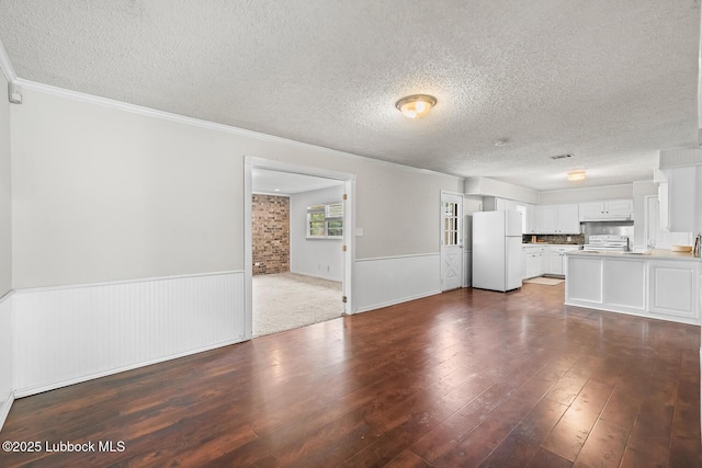 3415 39th St, Lubbock, TX 79413 - unfurnished living room featuring a textured ceiling, wainscoting, dark wood-style flooring, and crown molding