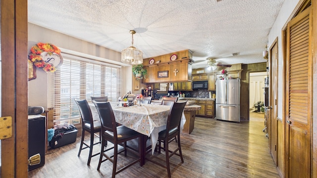 dining room with a textured ceiling, visible vents, dark wood-style floors, and ceiling fan with notable chandelier
