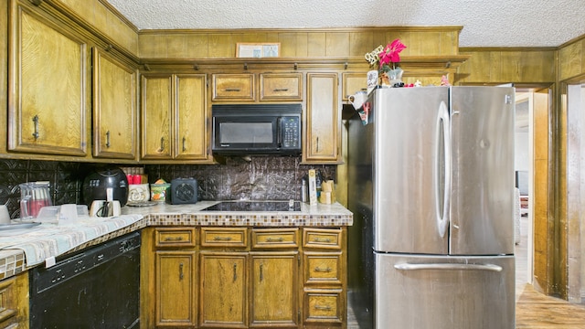 kitchen with tasteful backsplash, black appliances, a textured ceiling, and light countertops