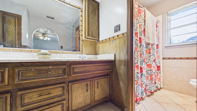 bathroom featuring tile patterned floors, wainscoting, tile walls, vanity, and visible vents